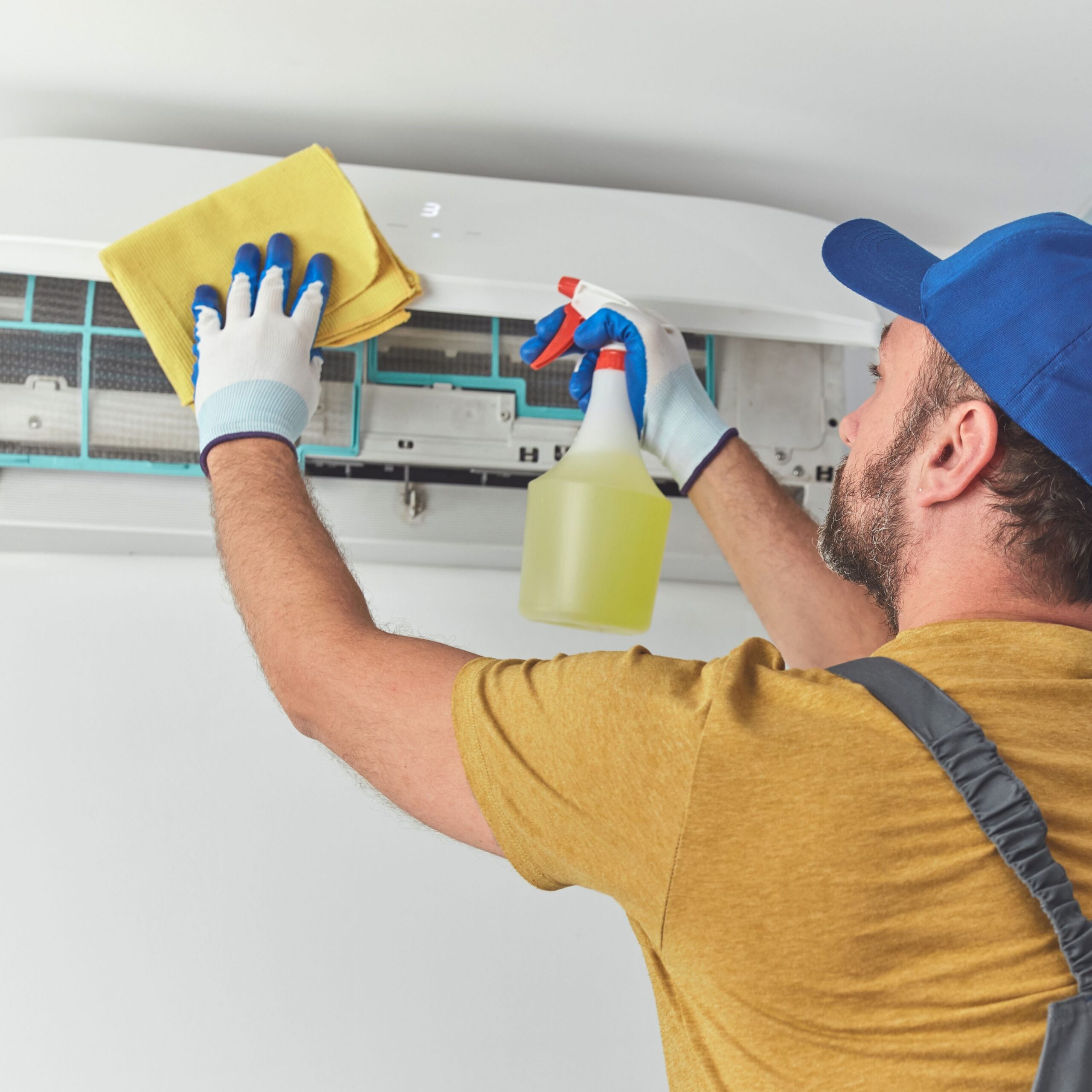 HVAC technician cleaning a wall-mounted air conditioner during an AC repair service in Des Moines