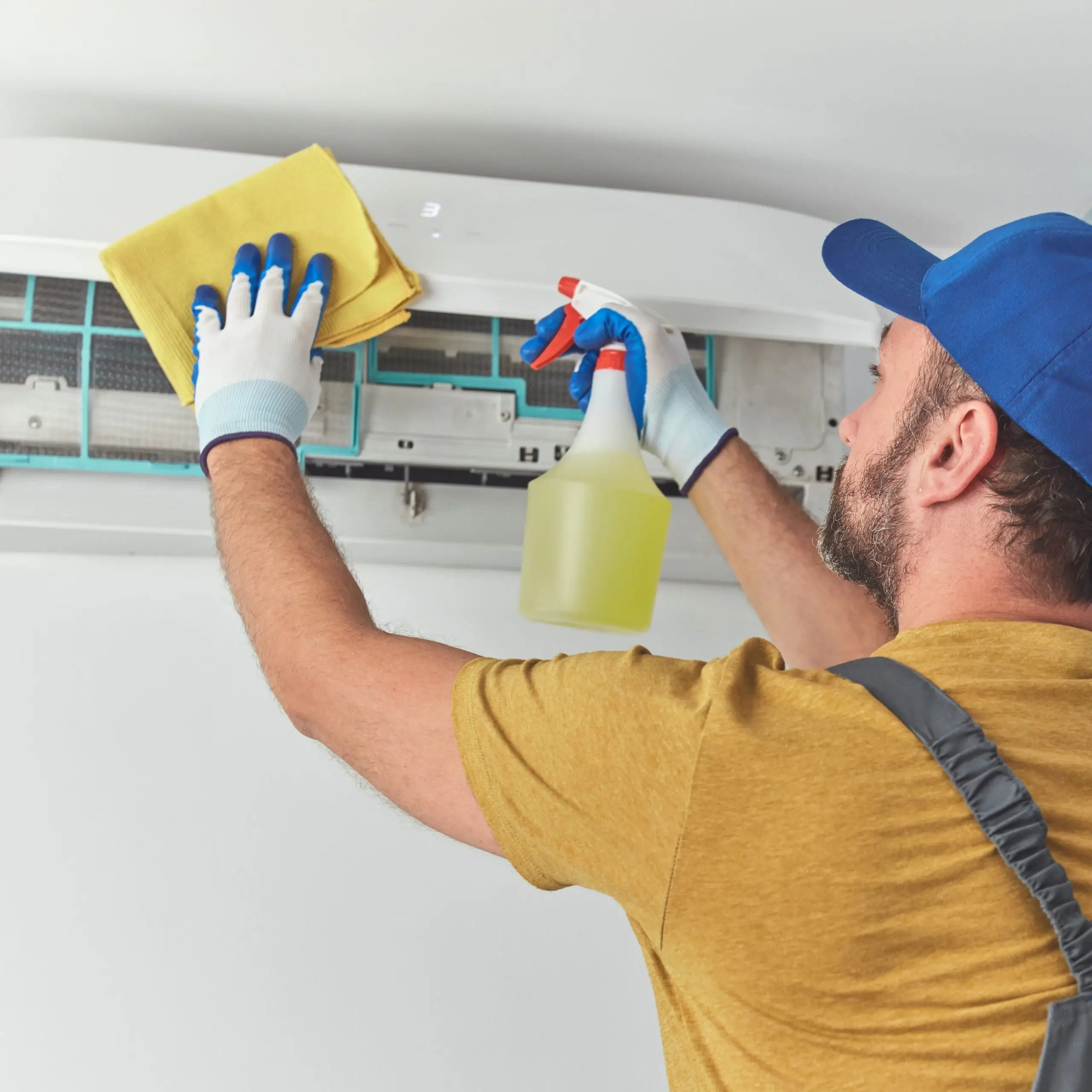 HVAC technician cleaning a wall-mounted air conditioner during an AC repair service in Des Moines